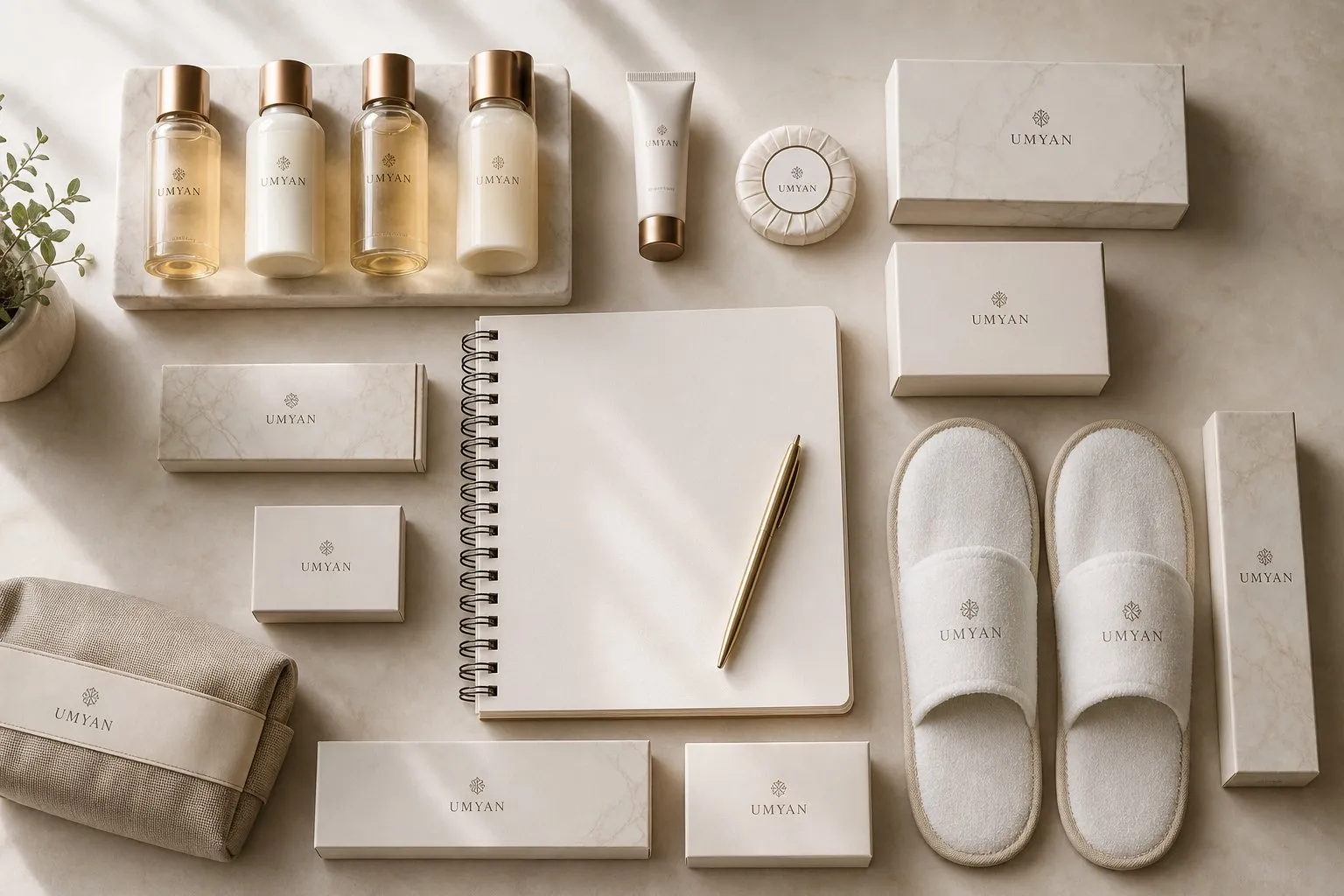 Custom hotel amenity program by UMYAN — bottles, soap, kit boxes and slippers around a design sketchbook
