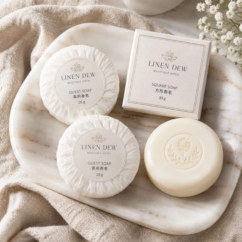 Hotel guest bar soap by UMYAN — pleated 25g round soaps and a boxed 30g square soap with embossed emblem on a marble tray