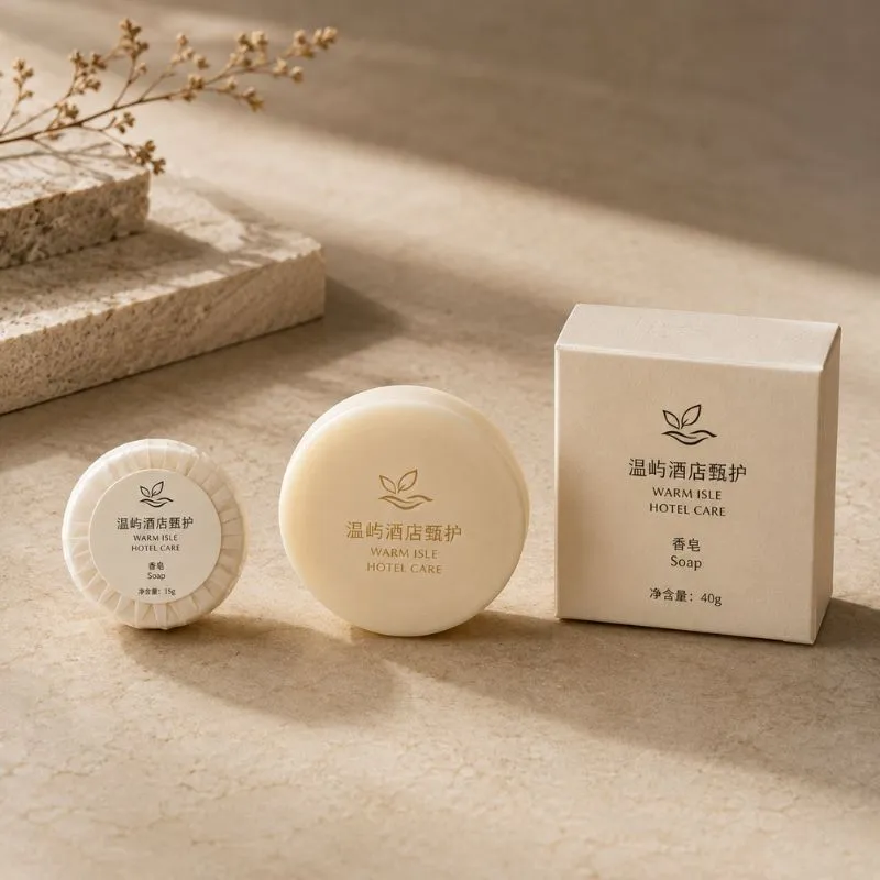 Hotel guest soap bars by UMYAN — a pleated 15g round soap, an unwrapped bar and a boxed 40g soap on a stone surface
